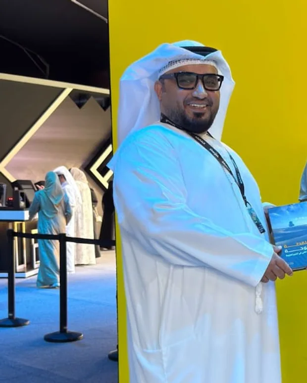أحمد الشحي في معرض اكسبوجر وهو يحمل كتابه «من اللقطة إلى اللوحة»